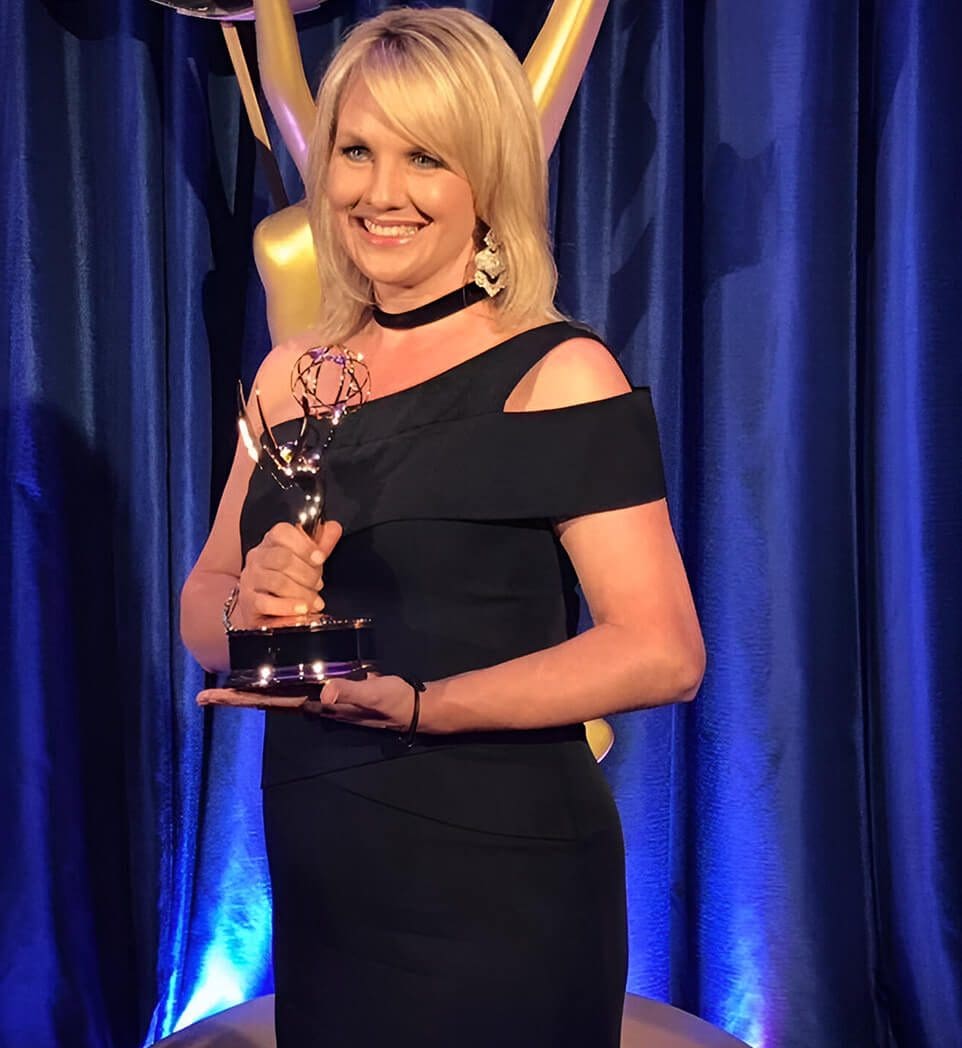 A woman in black dress holding an award.