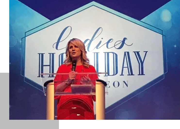 A woman in red is speaking at the podium.