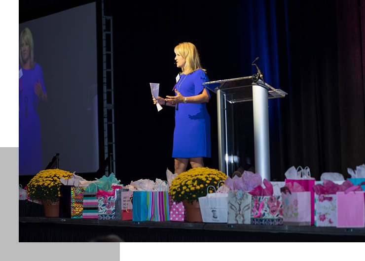 A woman standing at the podium with many bags of presents.